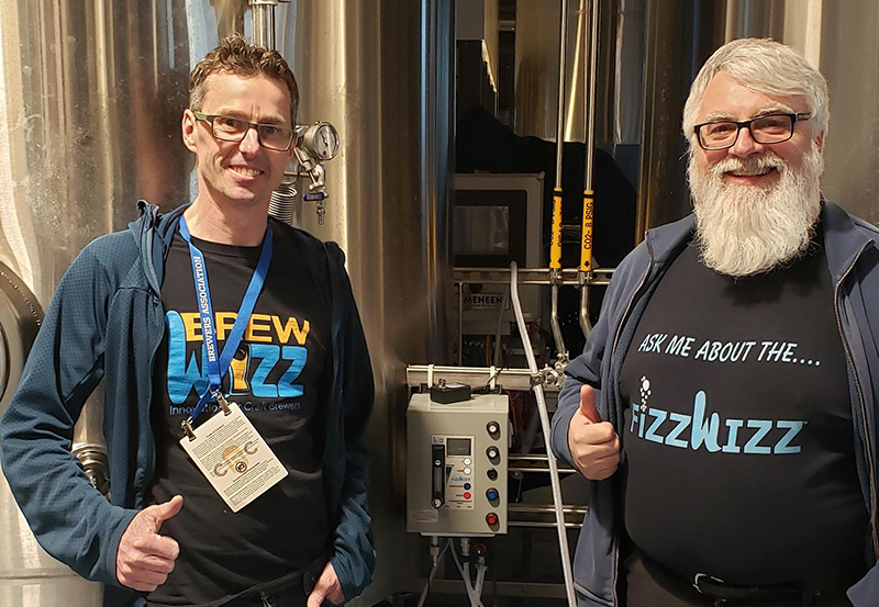 Guy Tipton and Cyril Meagher, founders of BrewWizz, standing with their creation, the FIZZWIZZ