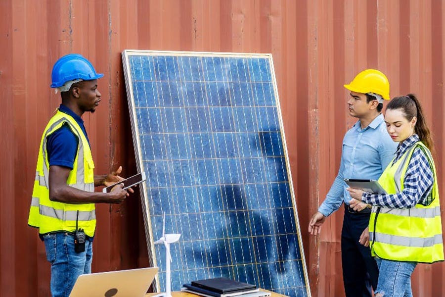A crew of workers has a discussion while installing a solar panel.