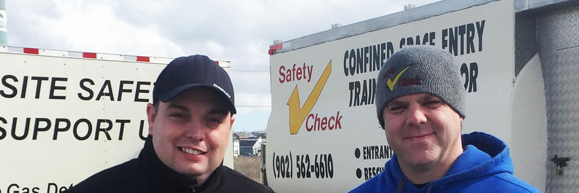 Two people standing in front of a Safety Check Inspections Limited training simulator