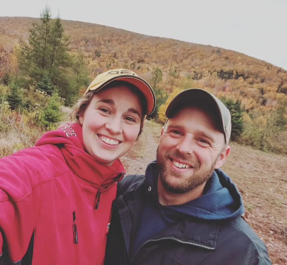 Man and woman taking a selfie in front of mountain and Fall leaves