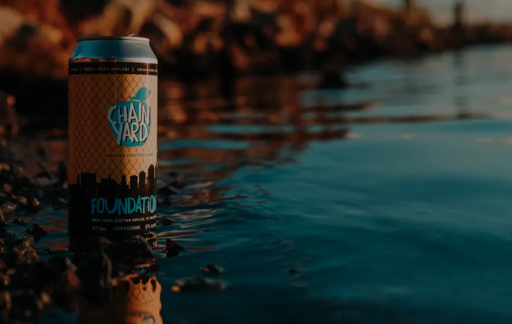 Can of Chain Yard Cidery cider poised at edge of ocean
