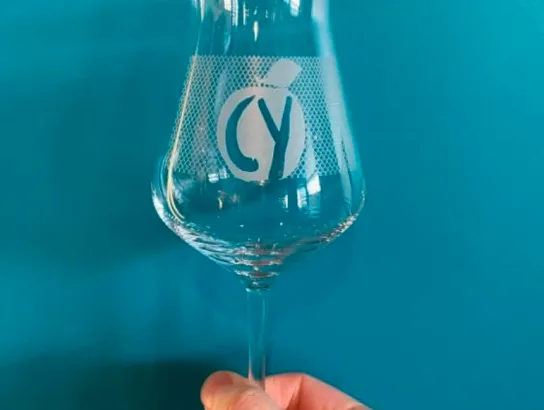 Chain Yard Cidery held in hand, blue background