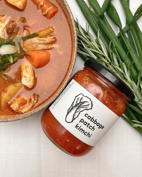 Bottle of kimchi next to bowl of soup