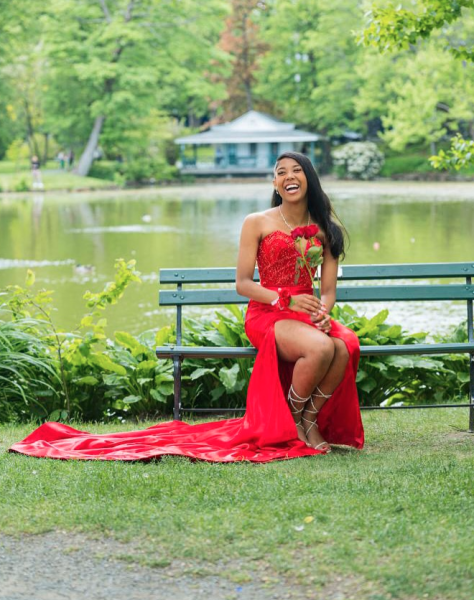 Girl in red gown seated on a bench