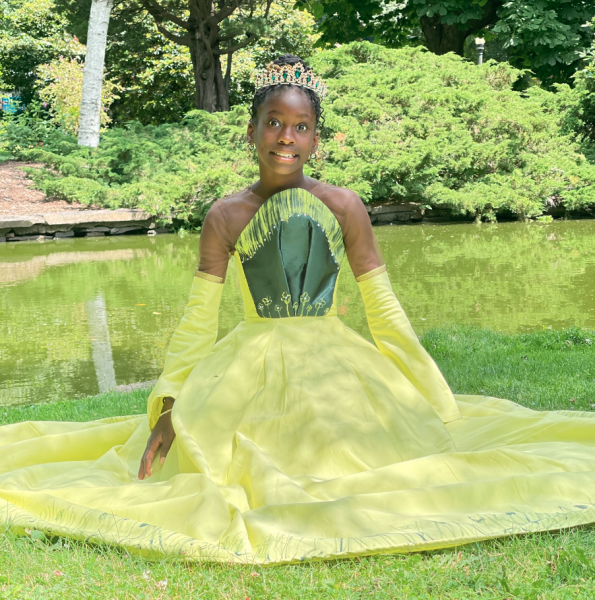 Girl in yellow and green gown sitting on the grass