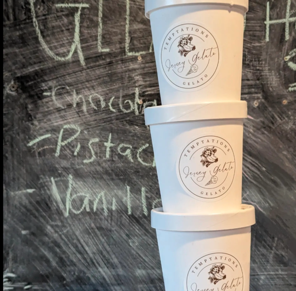 Three containers of gelato in front of chalkboard menu