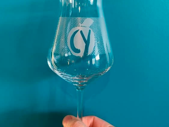 Chain Yard Cidery held in hand, blue background