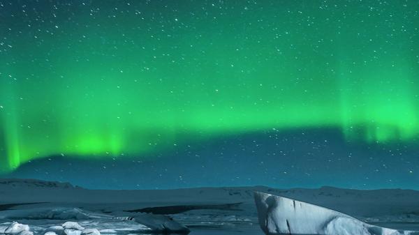 The northern lights in the sky above some ice floes in the water